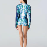 Woman wearing a blue and green patterned swimsuit on a light gray background