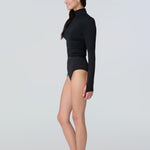 Side view of a woman wearing a black long-sleeve turtle neck rash-guard and bikini bottom.
