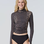 A woman wearing a long-sleeve mock neck rashguard in leopard and black bikini bottom