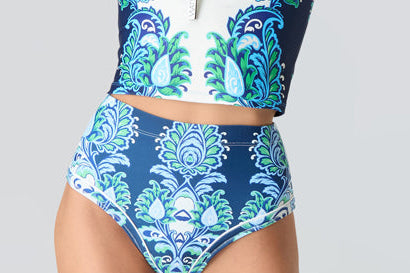 Woman wearing a blue and green floral 2 piece swimsuit on a white background