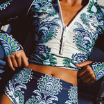 Woman wearing a blue and green floral patterned long sleeve 2 piece swimsuit