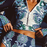 Woman wearing a blue and green floral patterned long sleeve 2 piece swimsuit