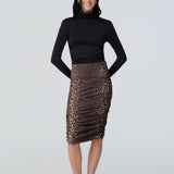 Front view of a woman wearing a black turtelneck adn leopard print midi skirt with side ruching.