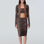 Front view of a woman wearing a leopard print zip front rashguard, bikini bralette, and midi skirt with side ruching.
