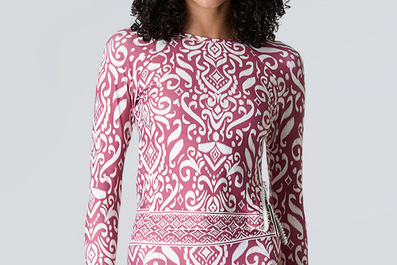 Woman wearing a pink and white patterned swimsuit against a gray background