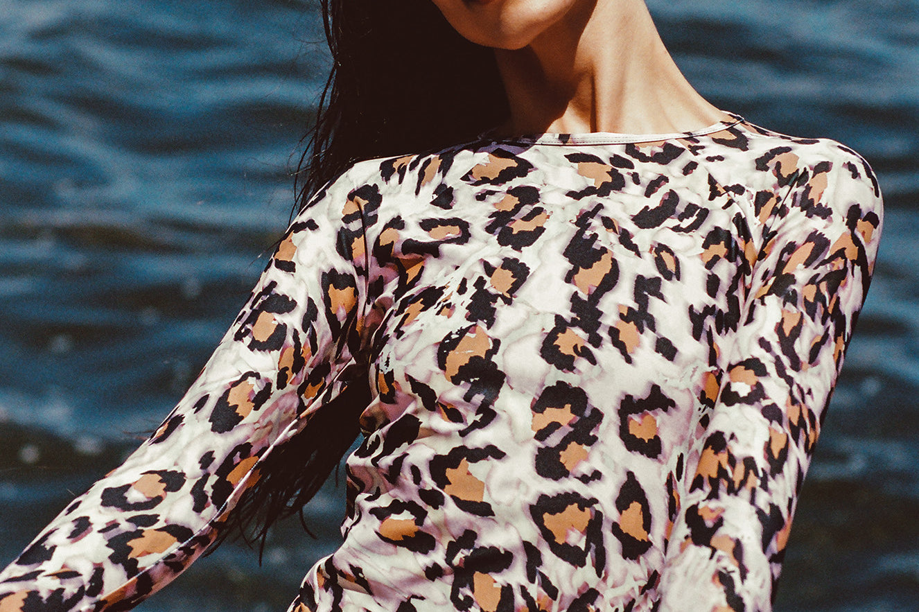 Female modeling Watskin Sasha rashguard and Belle bikini in Pink Leopard against ocean background