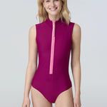 Front view of a woman wearing a sleeveless bodysuit in dark berry with pink zipper.