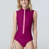Front view of a woman wearing a sleeveless bodysuit in dark berry with pink zipper.