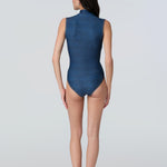 Back view of a woman in a side profile wearing a denim sleeveless one-piece swimsuit.
