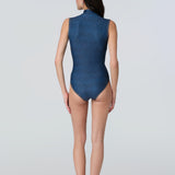 Back view of a woman in a side profile wearing a denim sleeveless one-piece swimsuit.