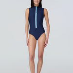 Front view of woman modeling a sleeveless navy blue one-piece swimsuit with a light blue front zipper.