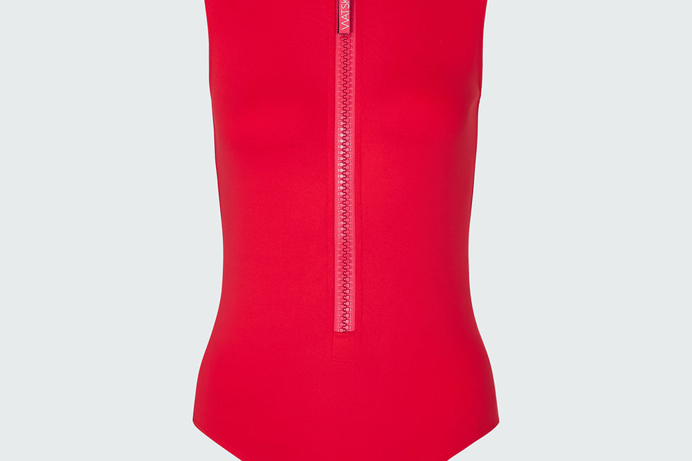 A red sleeveless bodysuit with a  mock neck and half-zip neckline.