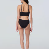 Back view of a woman wearing a black swim and sun protective bralette and bikini bottom.