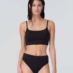 Front view of a woman wearing a black swim and sun protective bralette and bikini bottom.