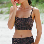 Woman wearing a leopard print swim & sun protective bralette and bikini bottom.