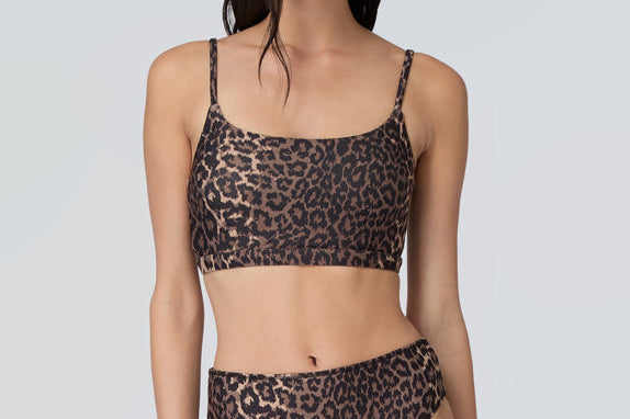 Front view of a woman wearing a leopard print swim and sun protective bralette and bikini bottom.