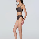 Side view of a woman wearing a leopard print swim and sun protective bralette and bikini bottom.