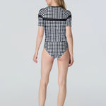 Back of a woman wearing a black and white checkered swimsuit on a light gray background