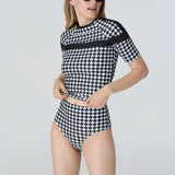 Woman wearing a black and white checkered swimsuit on a light gray background