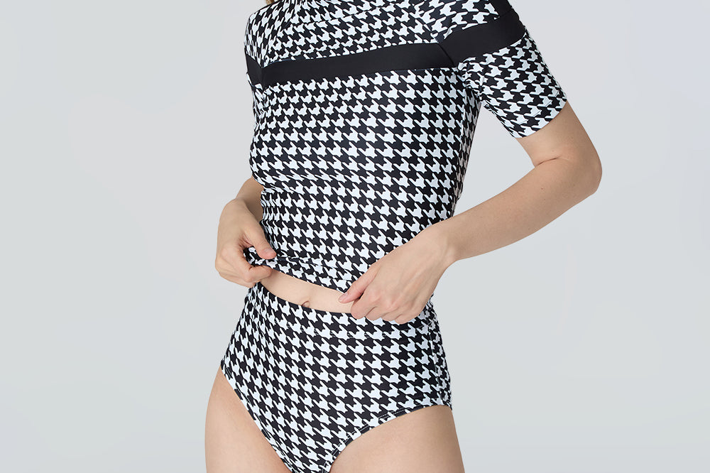 Woman wearing a black and white checkered swimsuit on a light gray background