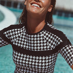 Woman wearing a black and white patterned top by a pool