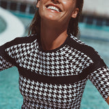 Woman wearing a black and white patterned top by a pool