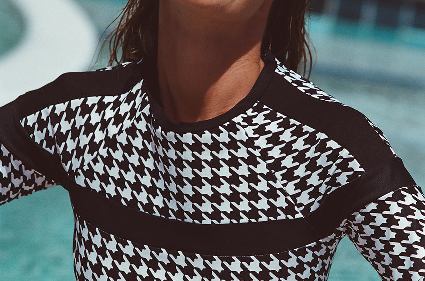 Woman wearing a black and white patterned top by a pool