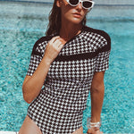 Woman in a black and white patterned swimsuit by a pool