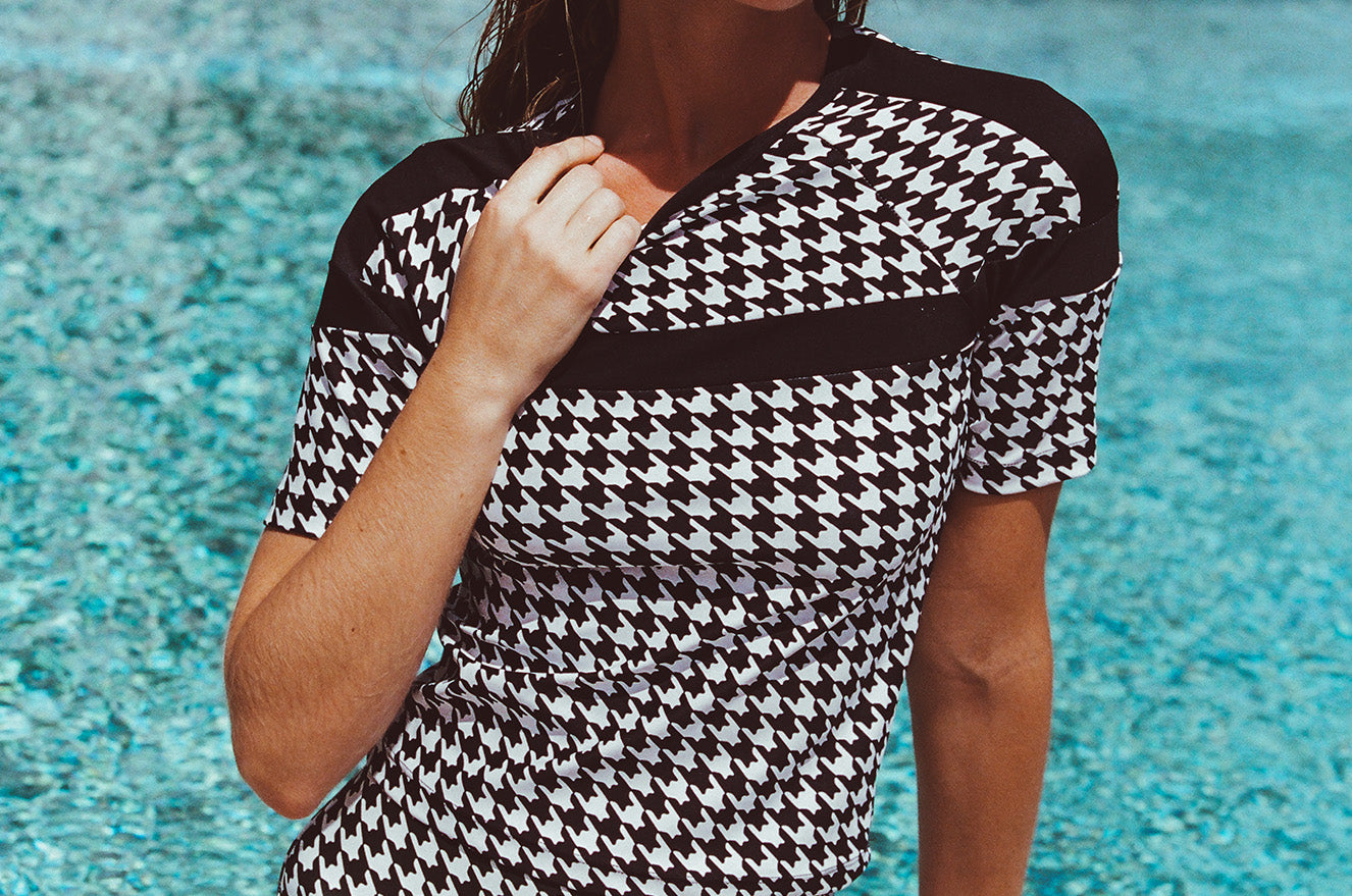 Woman in a black and white patterned swimsuit by a pool