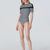 Woman wearing Watskin Coco short sleeve tee and bikini bottom in Black/Ivory houndstooth against a light gray background