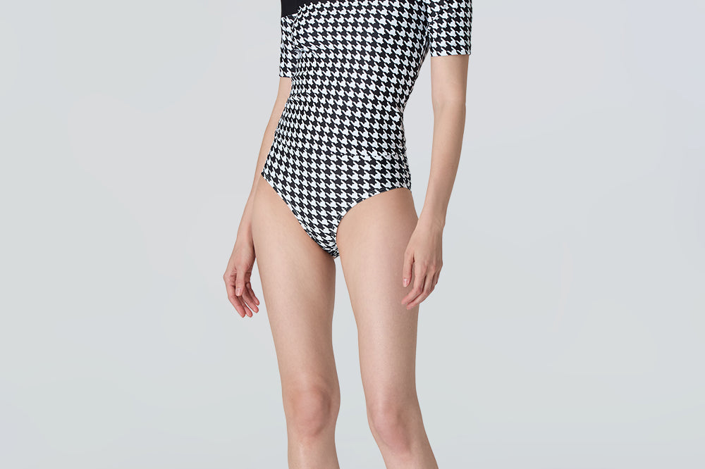 Woman wearing a black and white checkered swimsuit on a light gray background