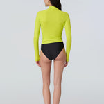 Back view of a woman wearing a lime green long-sleeve 1/2 zip rashguard with side ruching