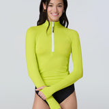 Front view of a woman wearing a lime green long-sleeve 1/2 zip rashguard with side ruching