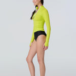 Side view of a woman wearing a bright lime green long-sleeve 1/2 zip rashguard with side ruching