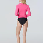 Back view of a woman wearing a pink long-sleeve rashguard with side ruching
