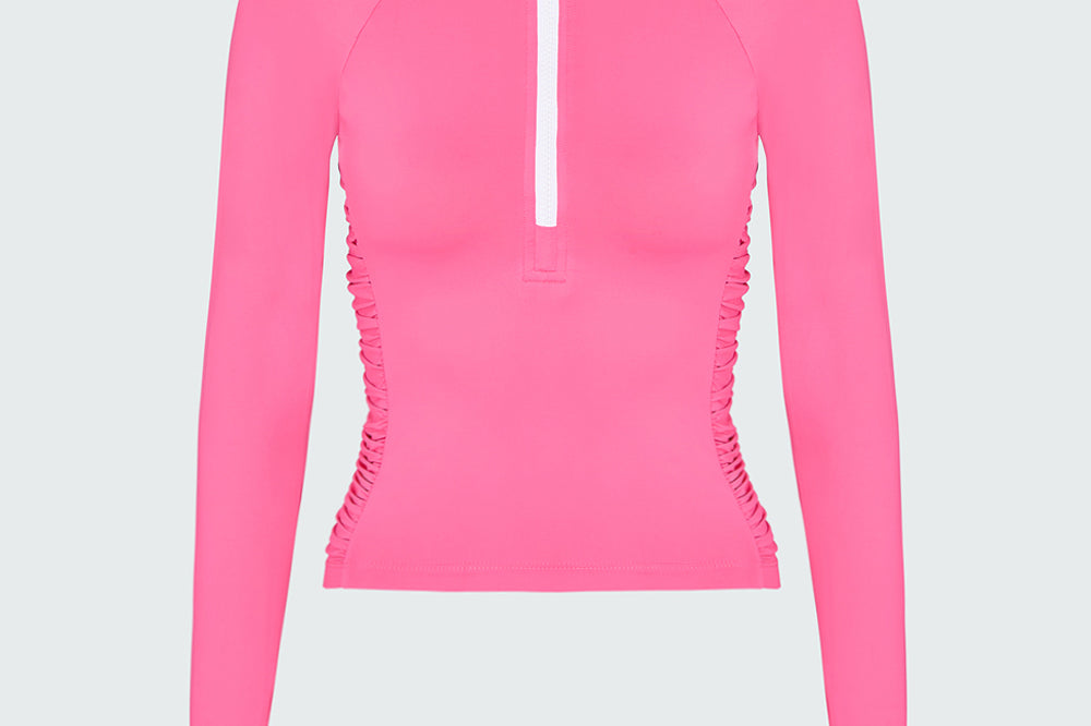 A pink long-sleeve 1/2 zip rashguard with side ruching