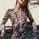 Woman wearing Watskin Ella long sleeved belted bodysuit in Animal Mix standing in a swimming pool leaning back against the edge of the tile