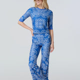 A woman wearing a short sleeve top and flare pants in a blue and white bandana print.