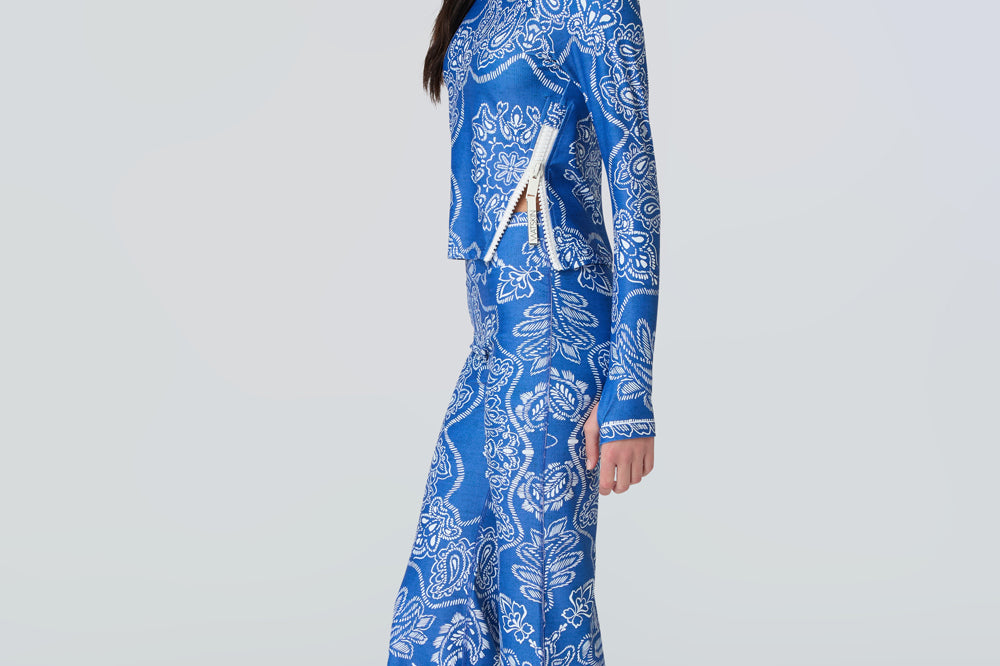A woman wearing a long sleeve top and flare pants in a blue and white bandana print.