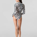 Rear view of woman modeling Watskin Kaia half-zip  long sleeve rashguard in Natural Zebra print with matching Belle bikini bottoms against a light gray background