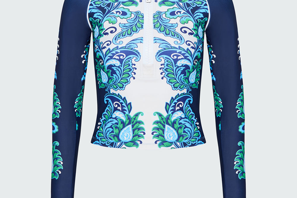 Navy, green and white floral patterned long-sleeve top on a light gray background