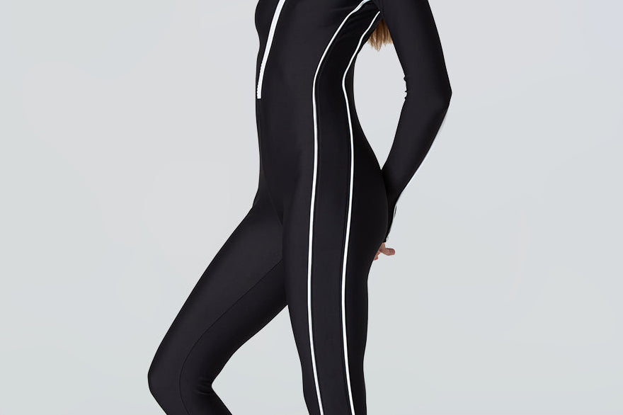 Woman wearing a black wetsuit with white stripes on a light gray background