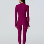 Back view of a woman wearing a long sleeve full length catsuit in dark berry with pink front zipper.