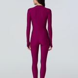 Back view of a woman wearing a long sleeve full length catsuit in dark berry with pink front zipper.