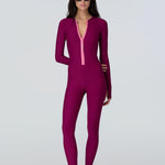 front view of a woman wearing a long sleeve full length catsuit in dark berry with pink front zipper.