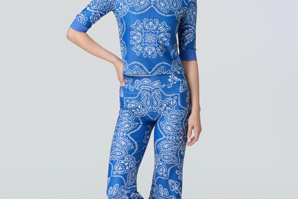 A woman wearing a short sleeve top and flare pants in a blue and white bandana print.