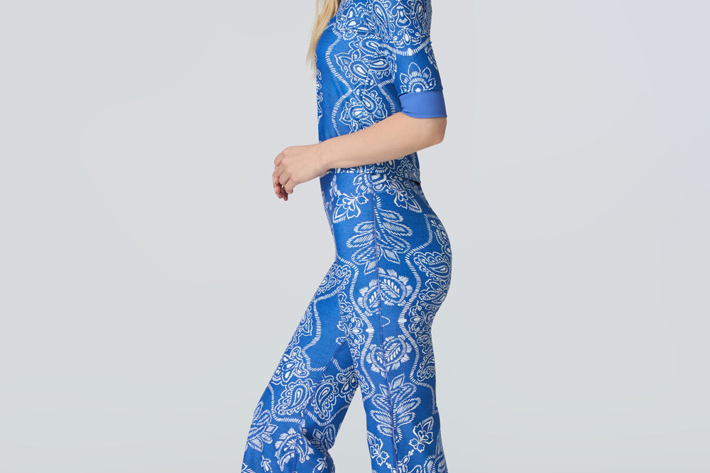 A woman wearing a short sleeve top and flare pants in a blue and white bandana print.