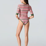 Full body back view of a woman wearing a pink and green wavy striped patterned short sleeve swim top with green sleeve cuff and bikini bottom with green trim on a white background
