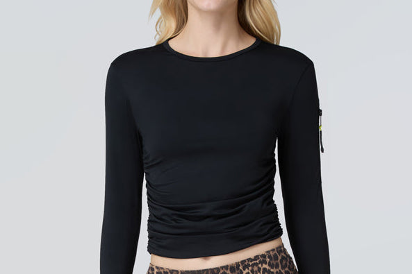 Front view of a woman wearing a black long-sleeve sun protective tee and black bikini bottom