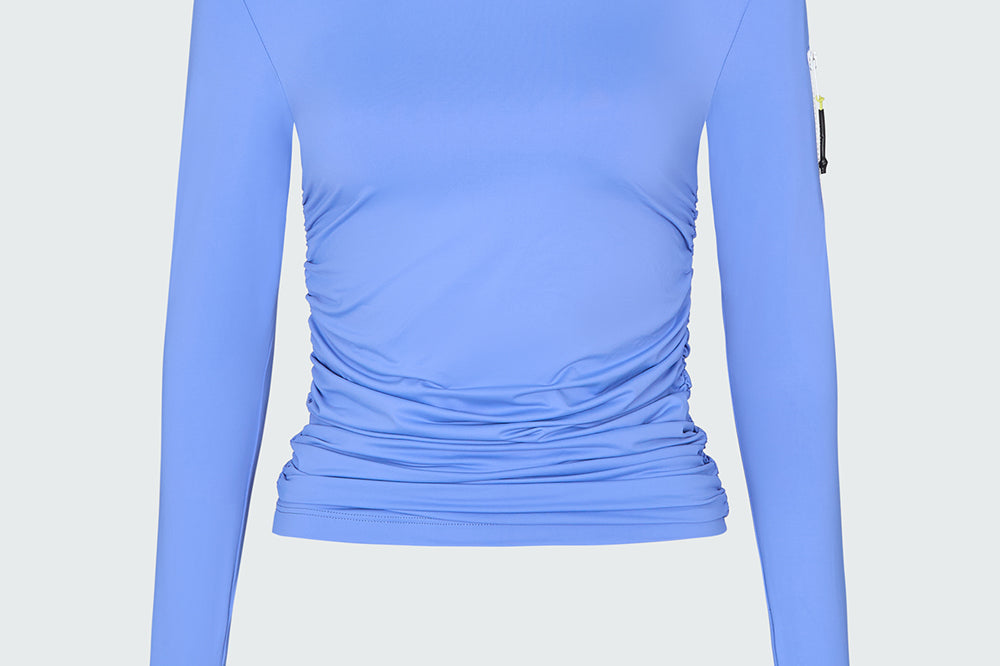 A light blue long-sleeve sun protective tee with side ruching and arm zip 